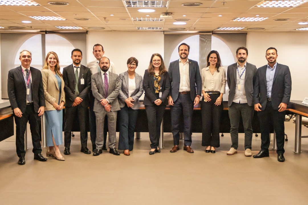 Mesa de reunião entre representantes da Anatel e da OCDE discutindo regulação de tecnologia