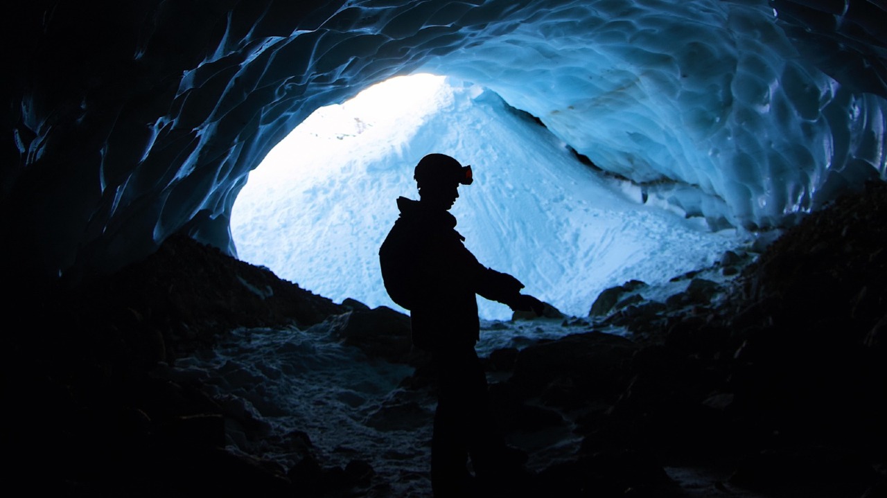 Homem em caverna analisando minerais estratégicos para tecnologia.