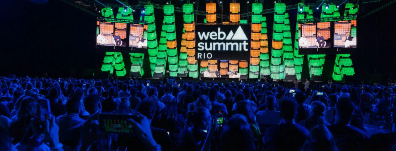 Logotipo do Web Summit Rio em destaque no telão de evento anterior.