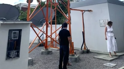 Torre de transmissão de TV digital e o logo da Anatel representando a infraestrutura de comunicações.